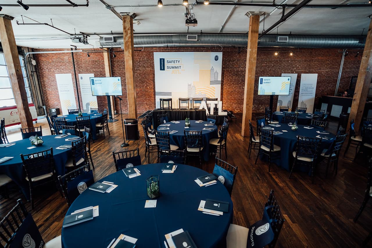 Safety Summit ATL setup with navy round tables and exposed brick