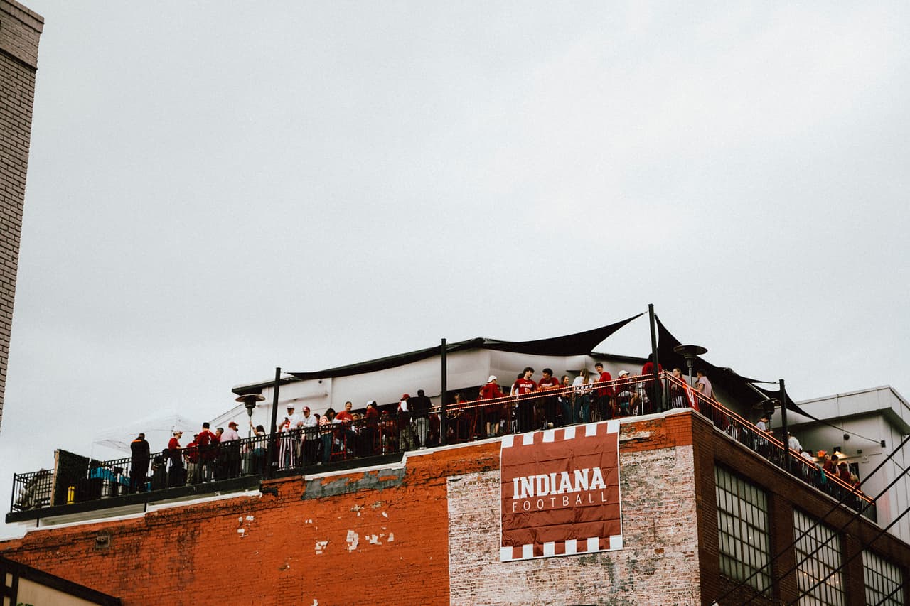 Rooftop party crowd above a football banner on brick