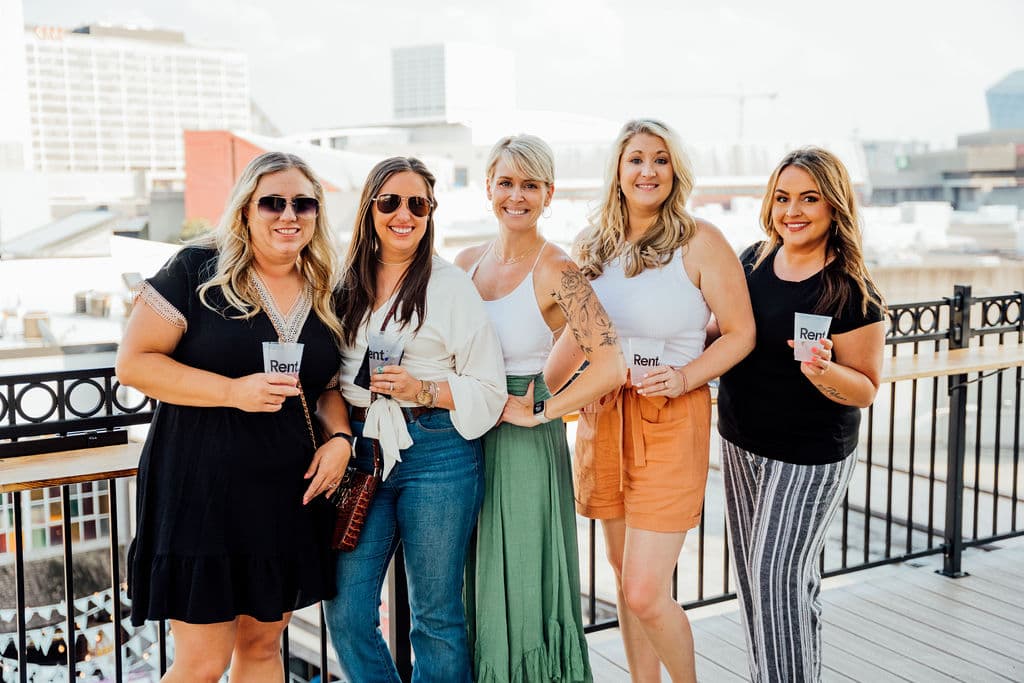 Group of coworkers with branded cups on the rooftop deck